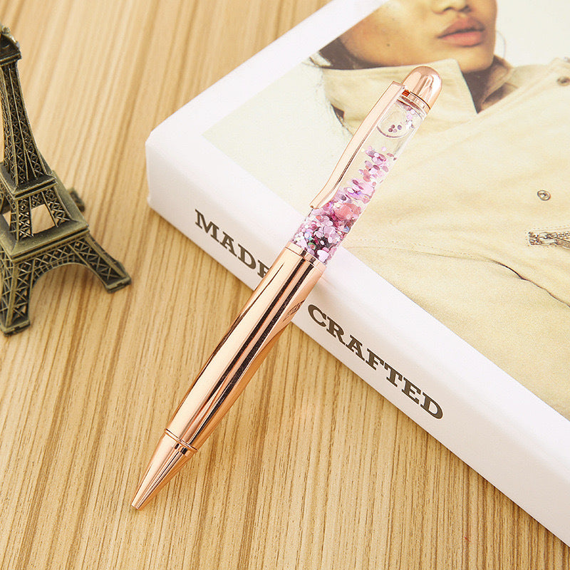 Stationery Large Fat Rose Gold Liquid Ball Pen on a wooden surface with an Eiffel Tower figurine.